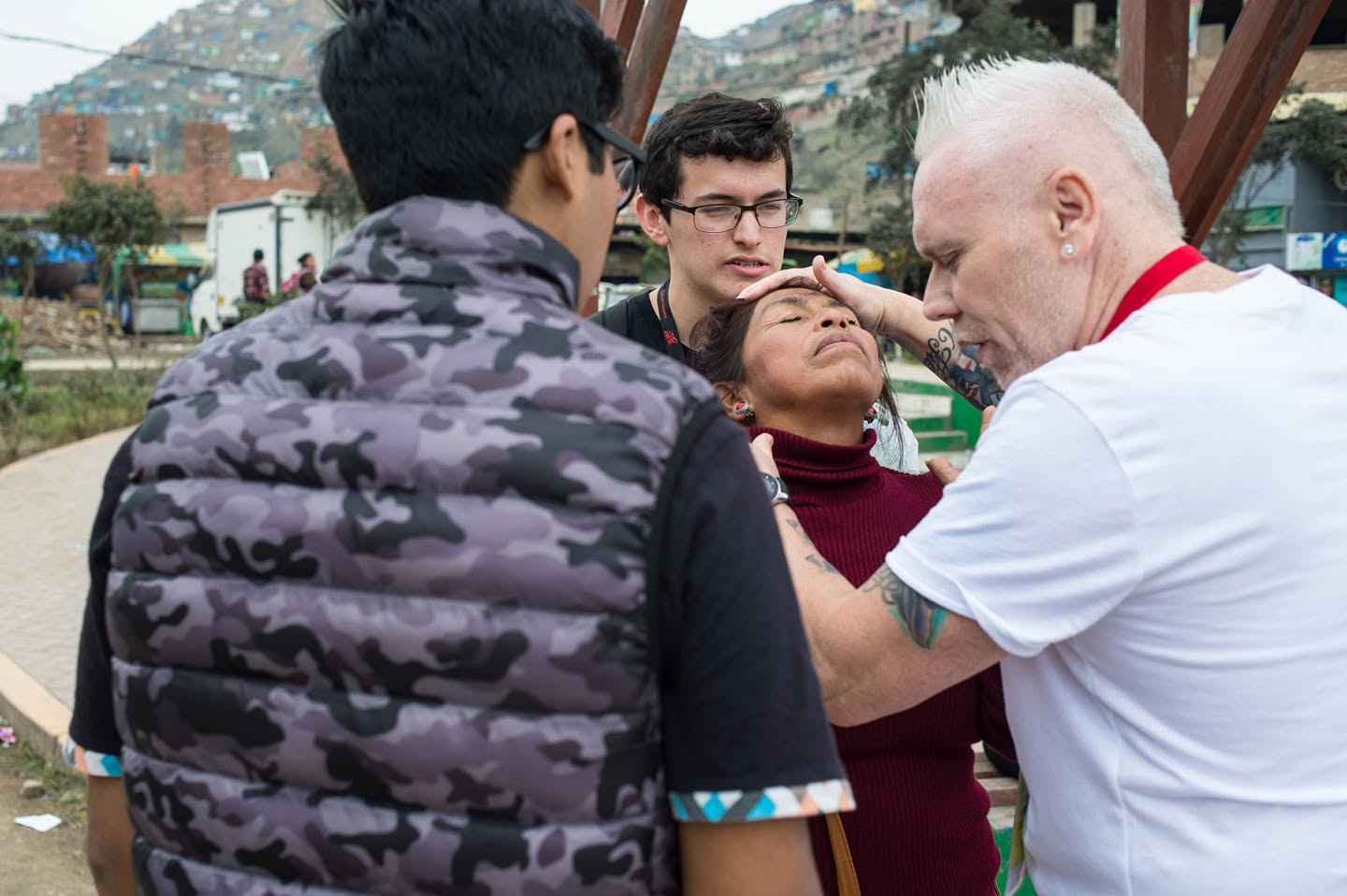 Pastor Michael Chamberlain praying with a woman during an outdoor mission outreach